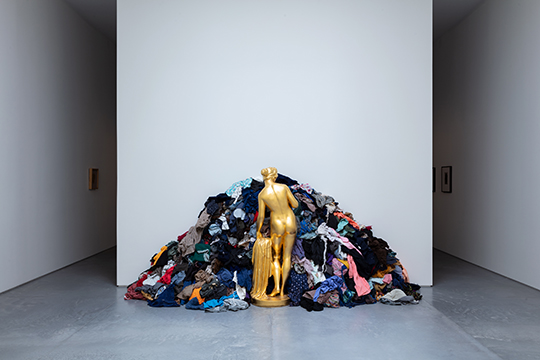 Sculpture of a female statue facing a pile of rags