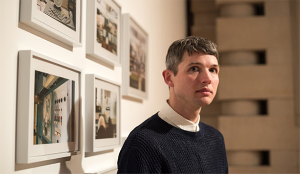 Luke Fowler stands in front of pictures of film stills