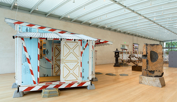 An image of the exhibition with the focus on a baby blue trailer with a slanted roof 