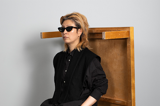 A woman wearing sunglasses sits within an upturned table.