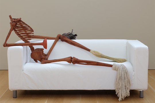 installation image of 'Laure', a sculpture of a wood skeleton with tools for hands and feet